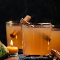 Cider in three glasses with cinnamon sticks.