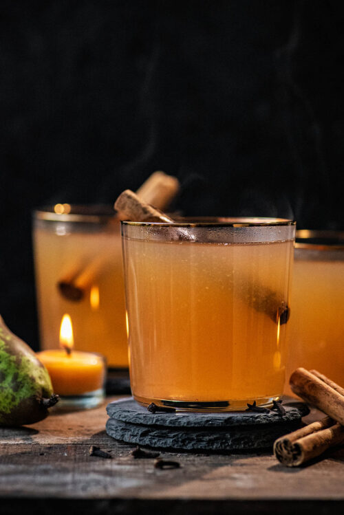 Cider in three glasses with cinnamon sticks.