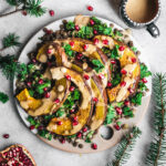 Pumpkin wedges on a platter with greens and lentils.