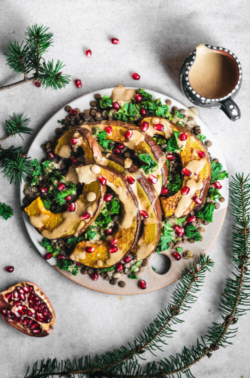 Pumpkin wedges on a platter with greens and lentils.