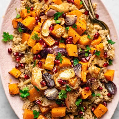Roasted pumpkin salad on a pink serving dish with pomegranate and parsley.