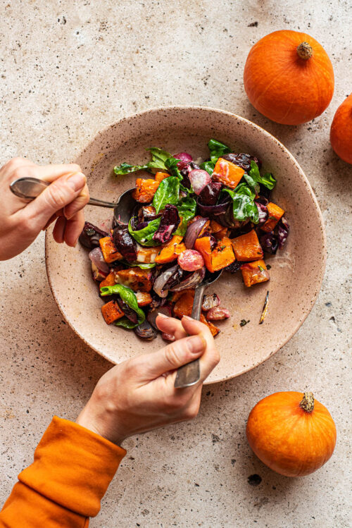Mixing pumpkin salad in a shallow bowl.