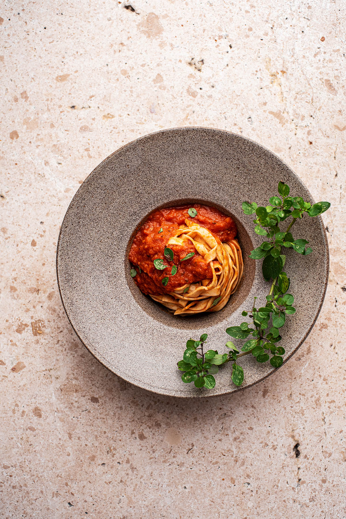 Pasta in a bowl with tomato sauce and oregano.