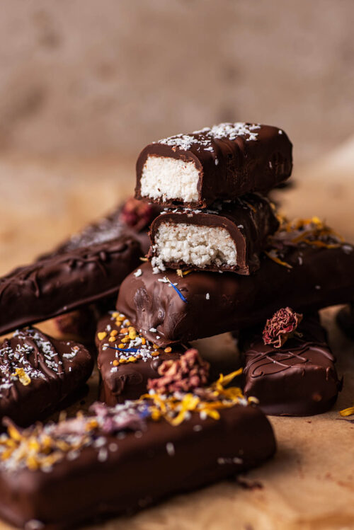 A halved coconut bar, cut side facing forward, on top of other bars.
