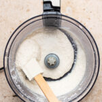 Finished coconut butter being moved with a spatula in the mixer.