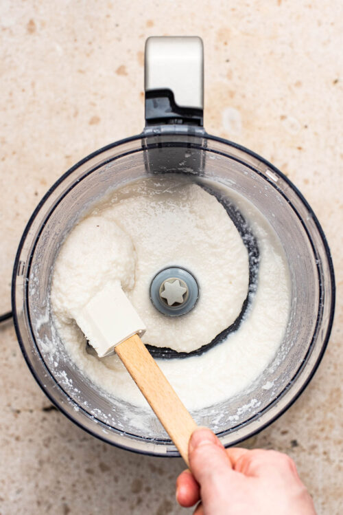 Finished coconut butter being moved with a spatula in the mixer.