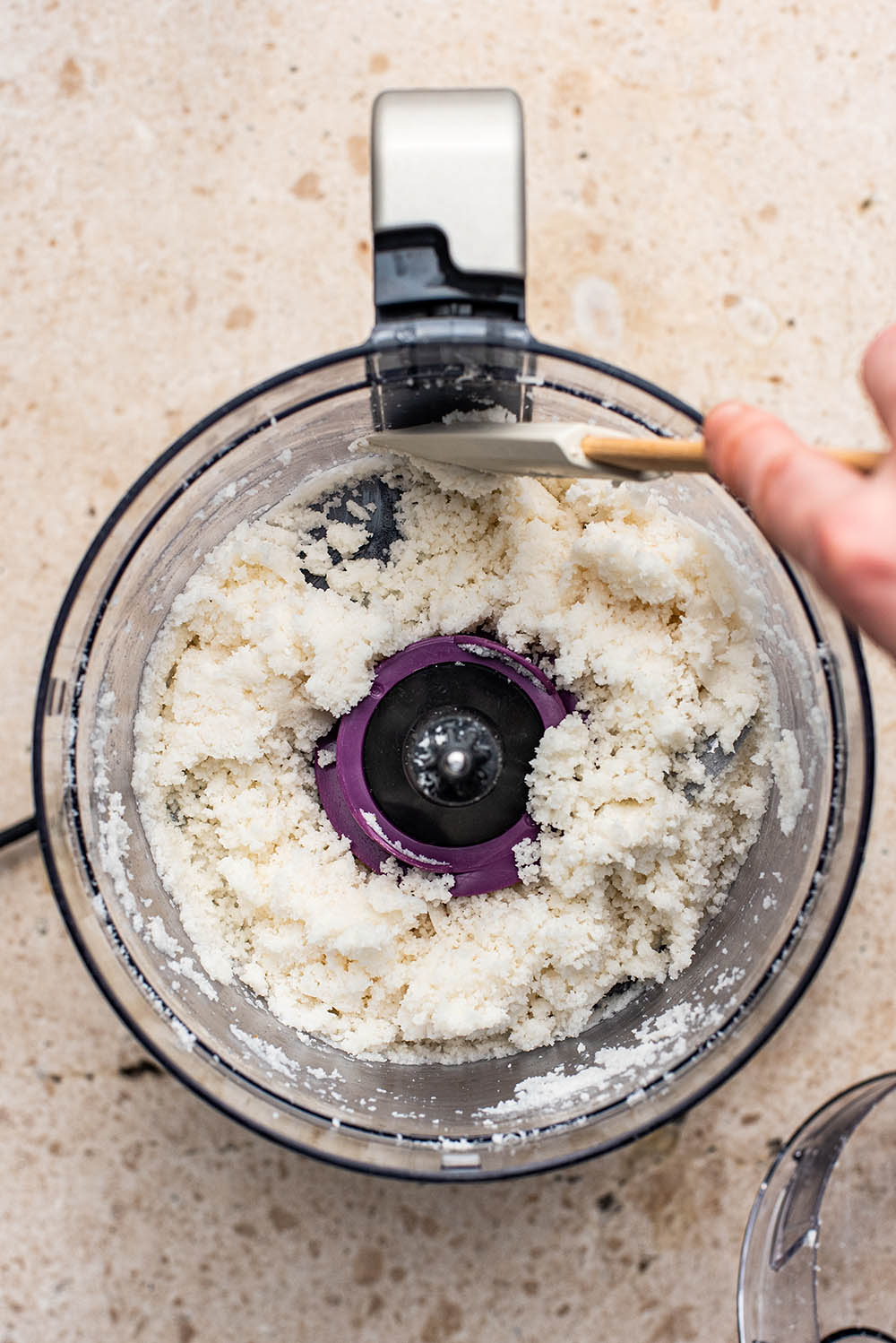 Scraping down the sides of the food processor.