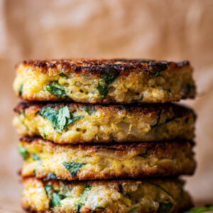 A stack of four quinoa patties on baking paper.