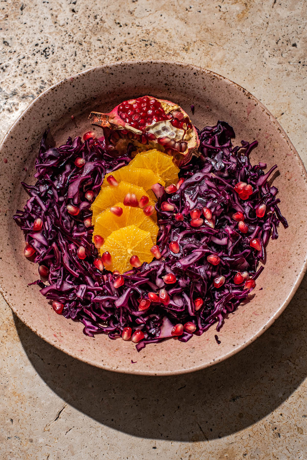 A shallow bowl of red cabbage salad with orange and pomegranate.