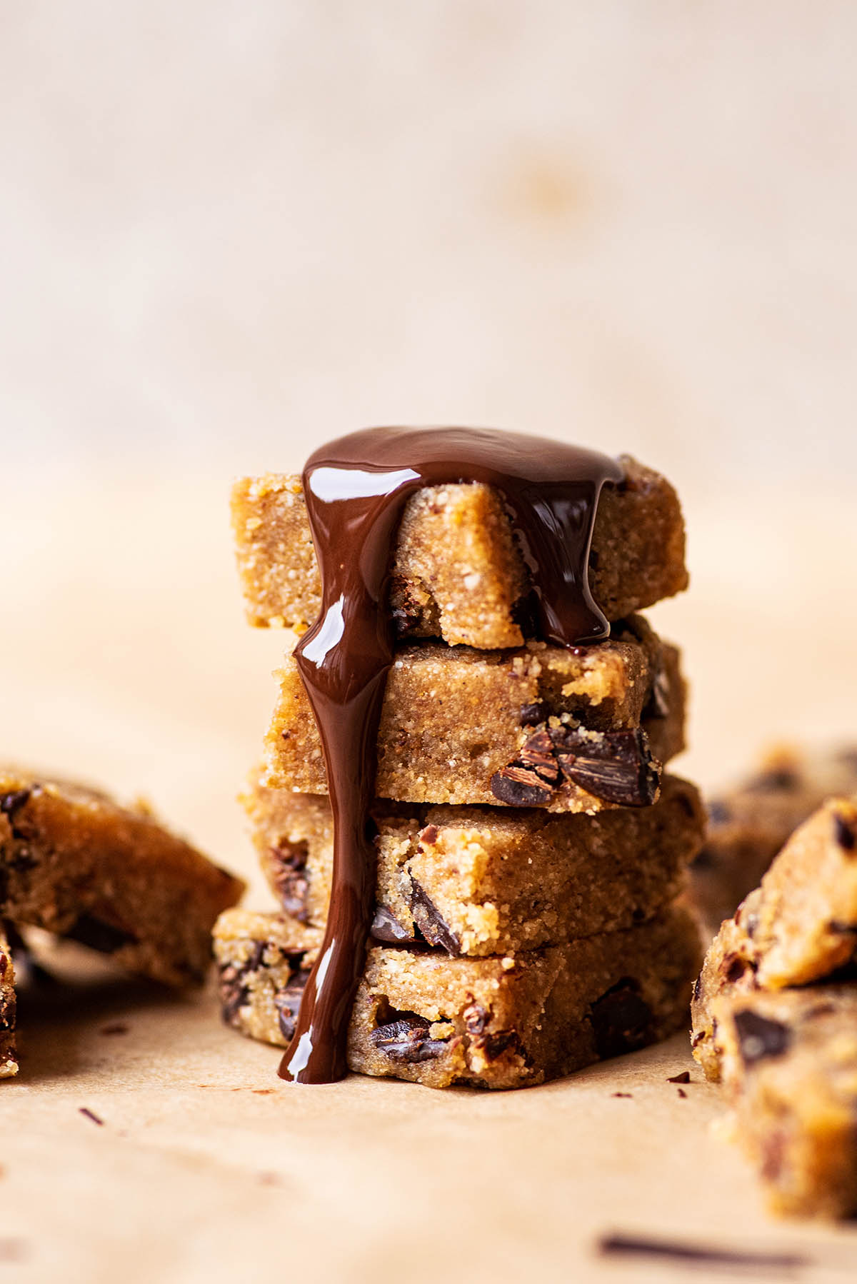 Melted chocolate topped stack of gluten free cookie dough squares..