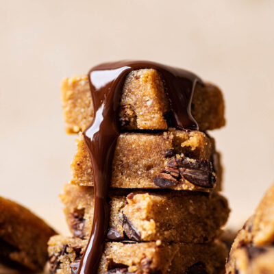 Melted chocolate topped stack of gluten free cookie dough squares..