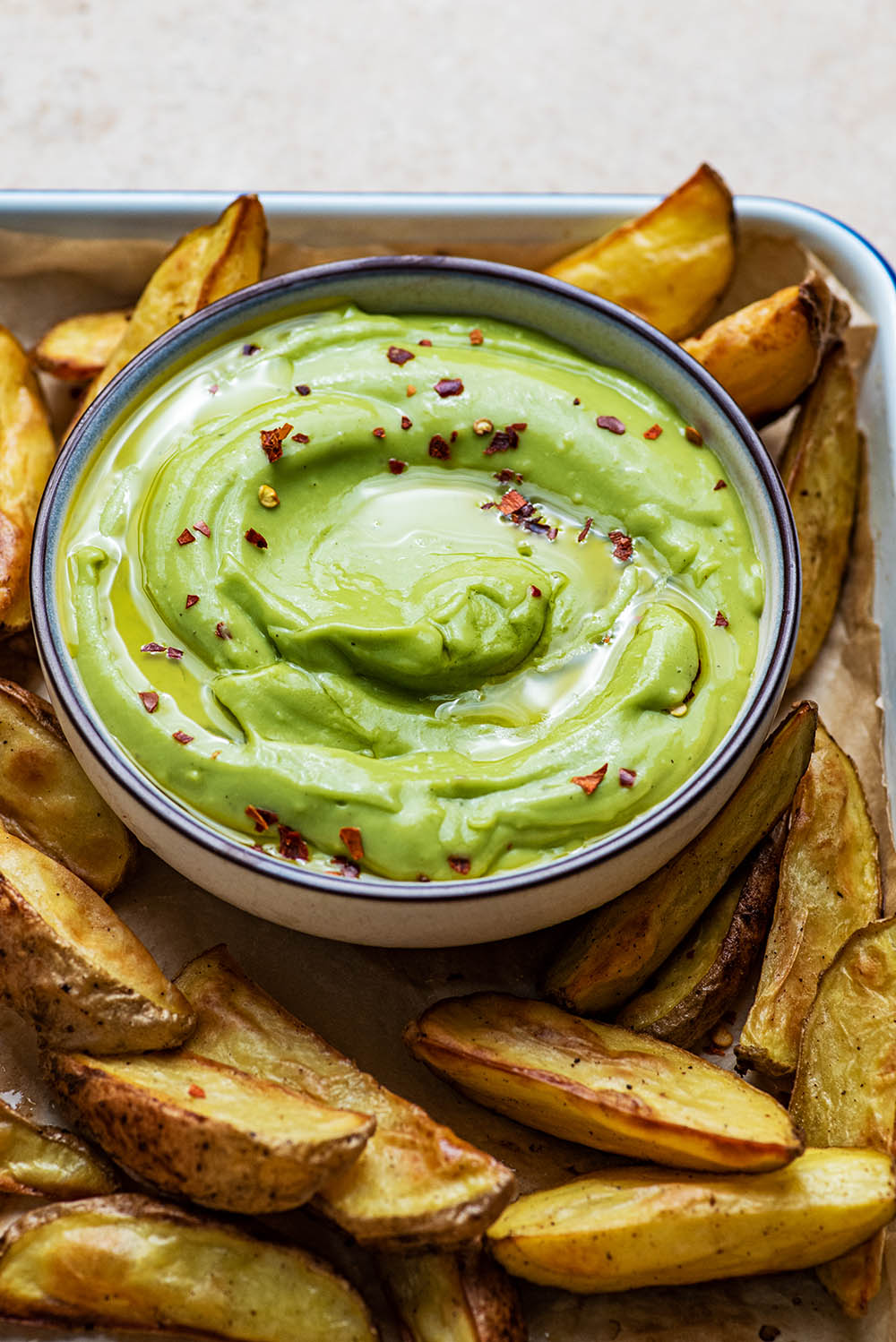 Aioli topped with hot pepper flakes, surrounded by wedges.