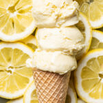 Three scoops of ice cream on a cone, on top of a pile of lemon slices.