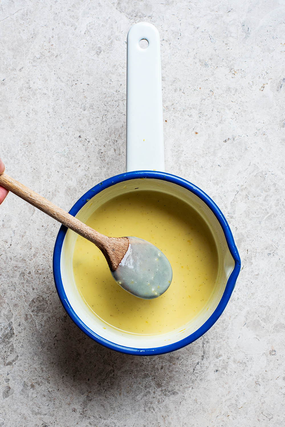 Wooden spoon dipped into the custard to show coating.