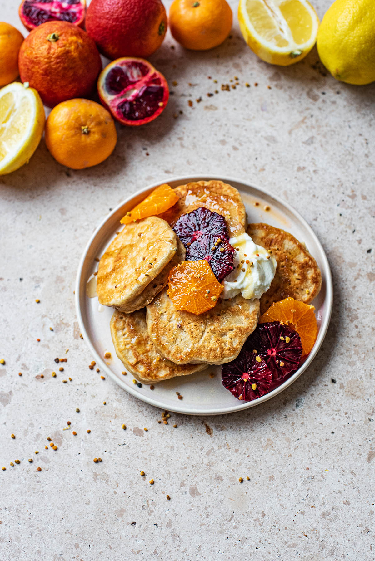A plate of pancakes with yogurt and orange slices.