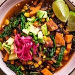Close up of a bowl of sweet potato chili with avocado and pickled onion.