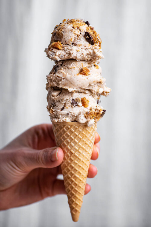 Three scoops on ice cream on a small sugar cone.