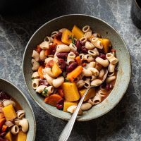 A bowl of minestrone with a spoon.