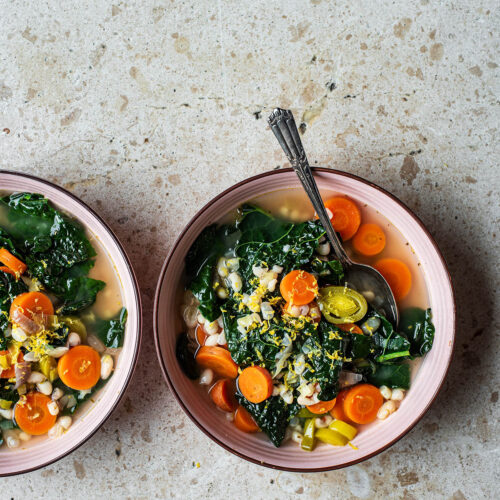 Two bowls of soup, one with a spoon.