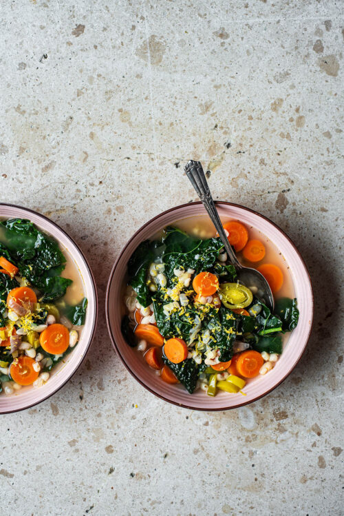 Two bowls of soup, one with a spoon.
