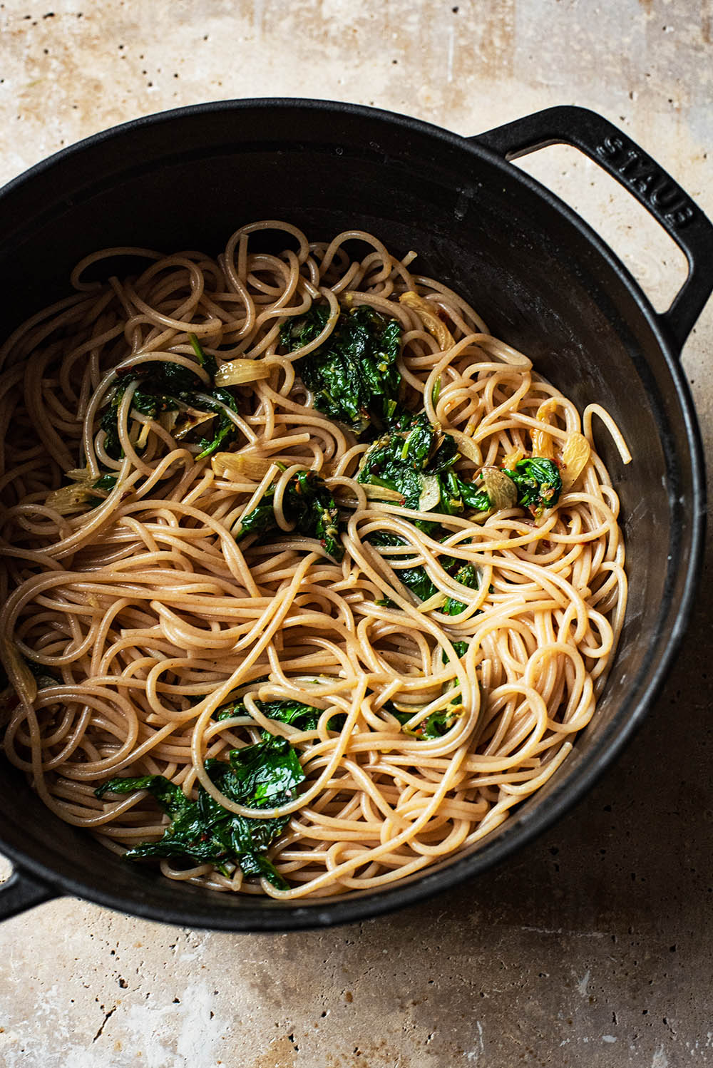 Pasta mixed with spinach and garlic in a pot.