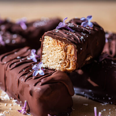 Close up showing halved date caramel chocolate bar with lilac flowers.