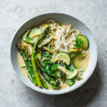 Rice noodles and green vegetables in coconut milk broth.