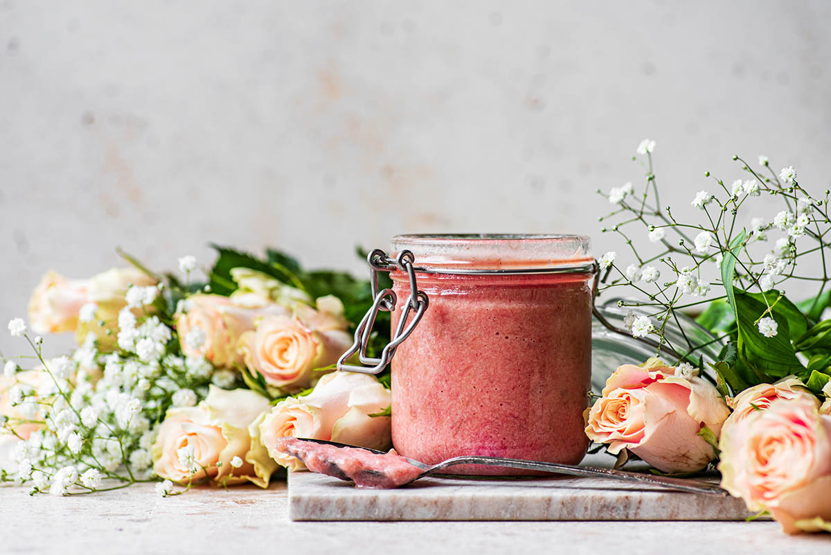 A jar of curd with roses and baby's breath.