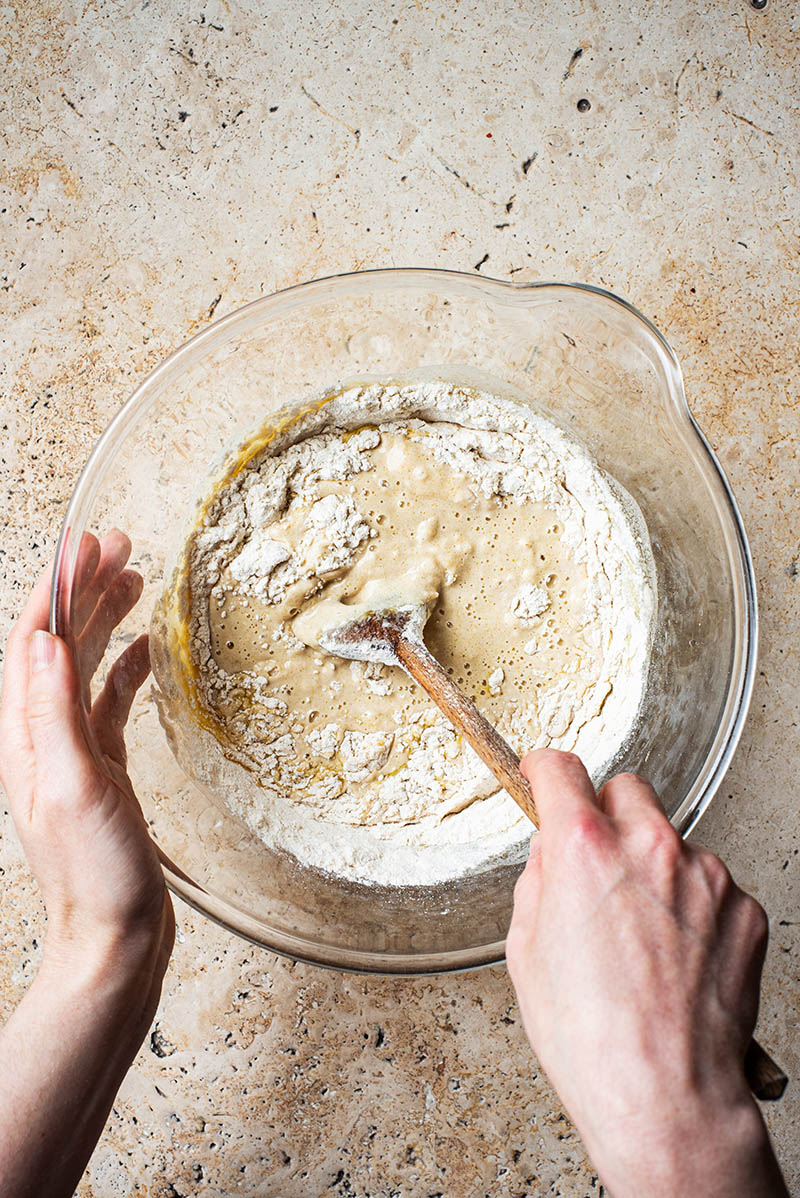 Woman's hands stirring flour into the dough.