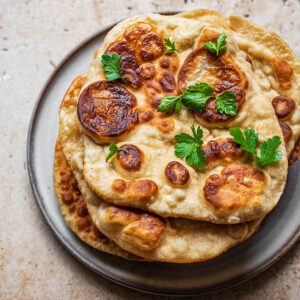 A stack of naan with parsley on top.