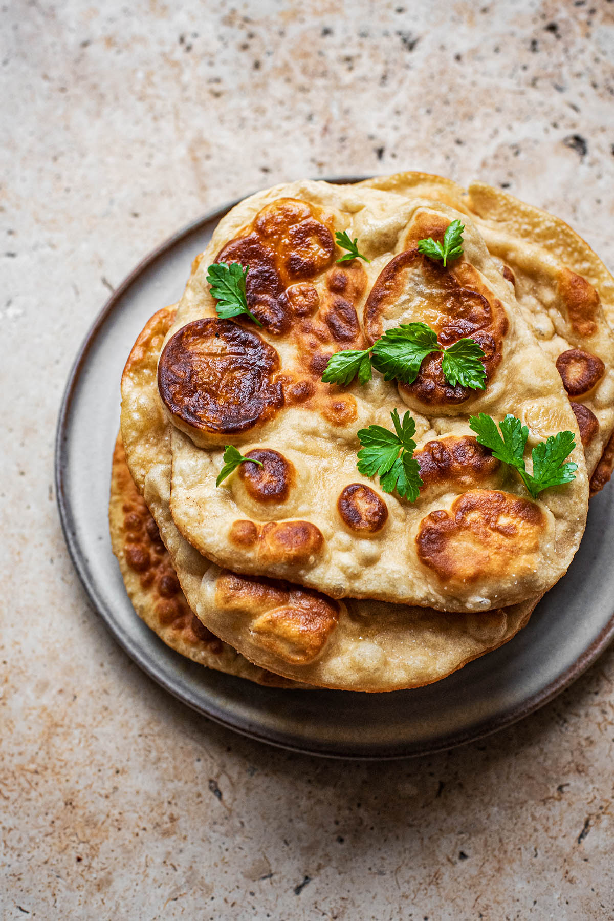 A stack of naan with parsley on top.