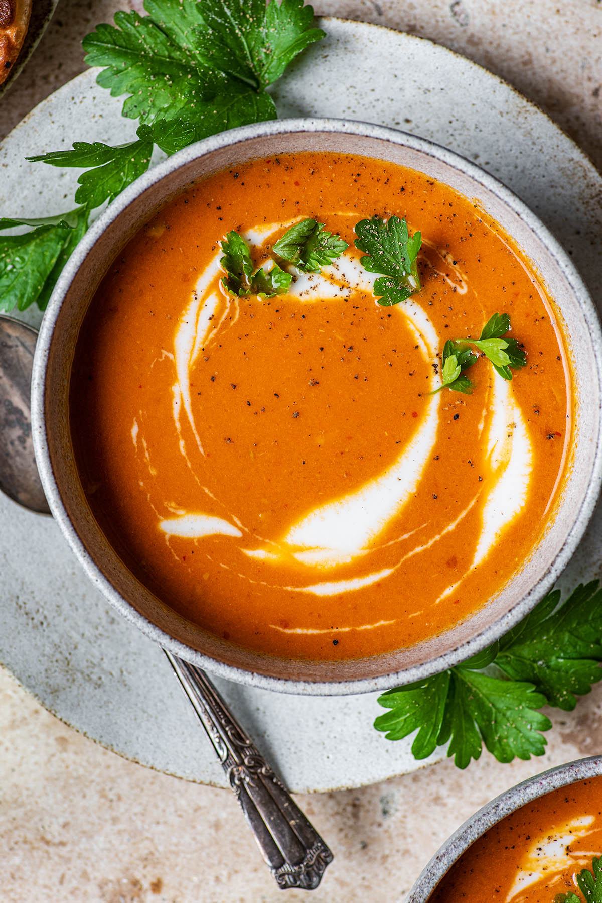 Close up of tomato soup topped with a swirl of yogurt and parsley.
