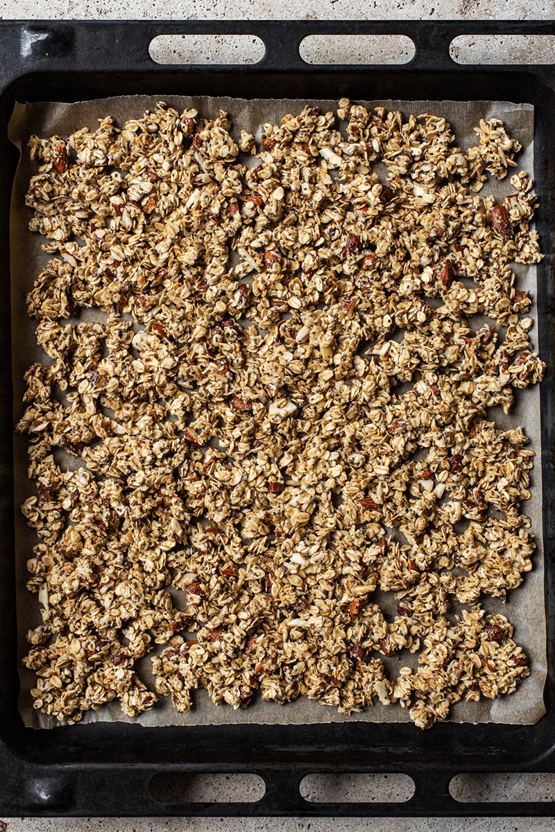Unbaked granola spread onto a large baking sheet.