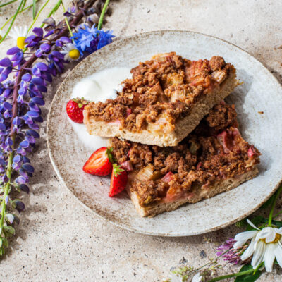 Two pieces of cake on a plate with wildflowers around.