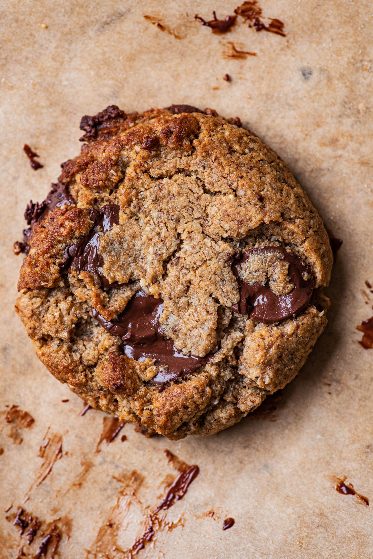 Close up of a chocolate chip cookie on parchment paper.