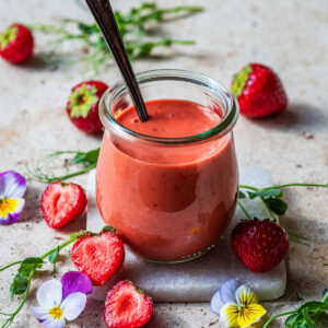 Small jar of vinaigrette with strawberries and flowers.