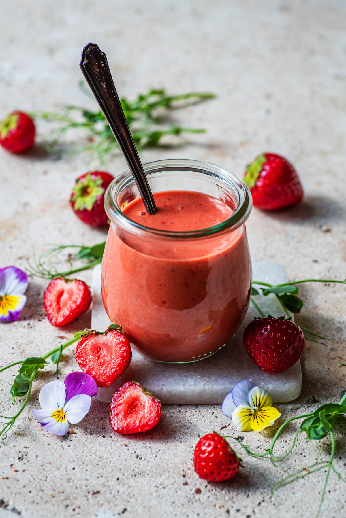 Small jar of vinaigrette with strawberries and flowers.
