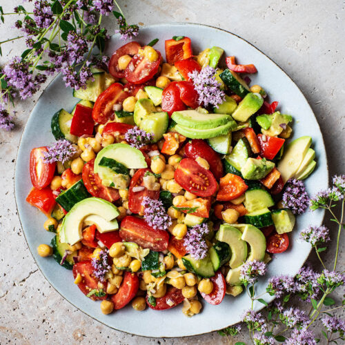 A platter filled with chickpea salad with tomatoes, avocado, and other summer vegetables.