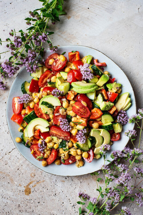 A platter filled with chickpea salad with tomatoes, avocado, and other summer vegetables.