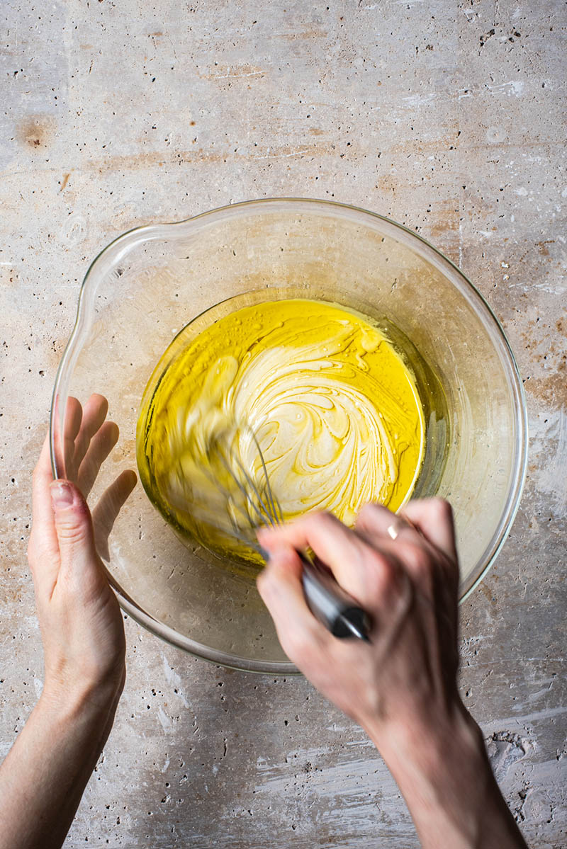 Woman's hands whisking wet ingredients in a large bowl.