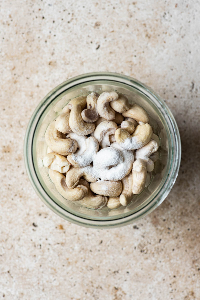 Soaked cashews and probiotic powder in a mixing container.