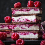Stack of four bars with more behind, and raspberries around.