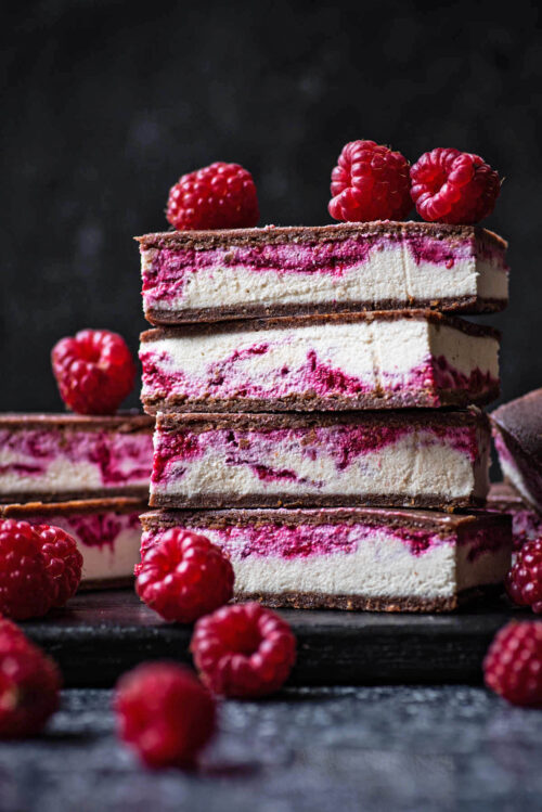 Stack of four bars with more behind, and raspberries around.
