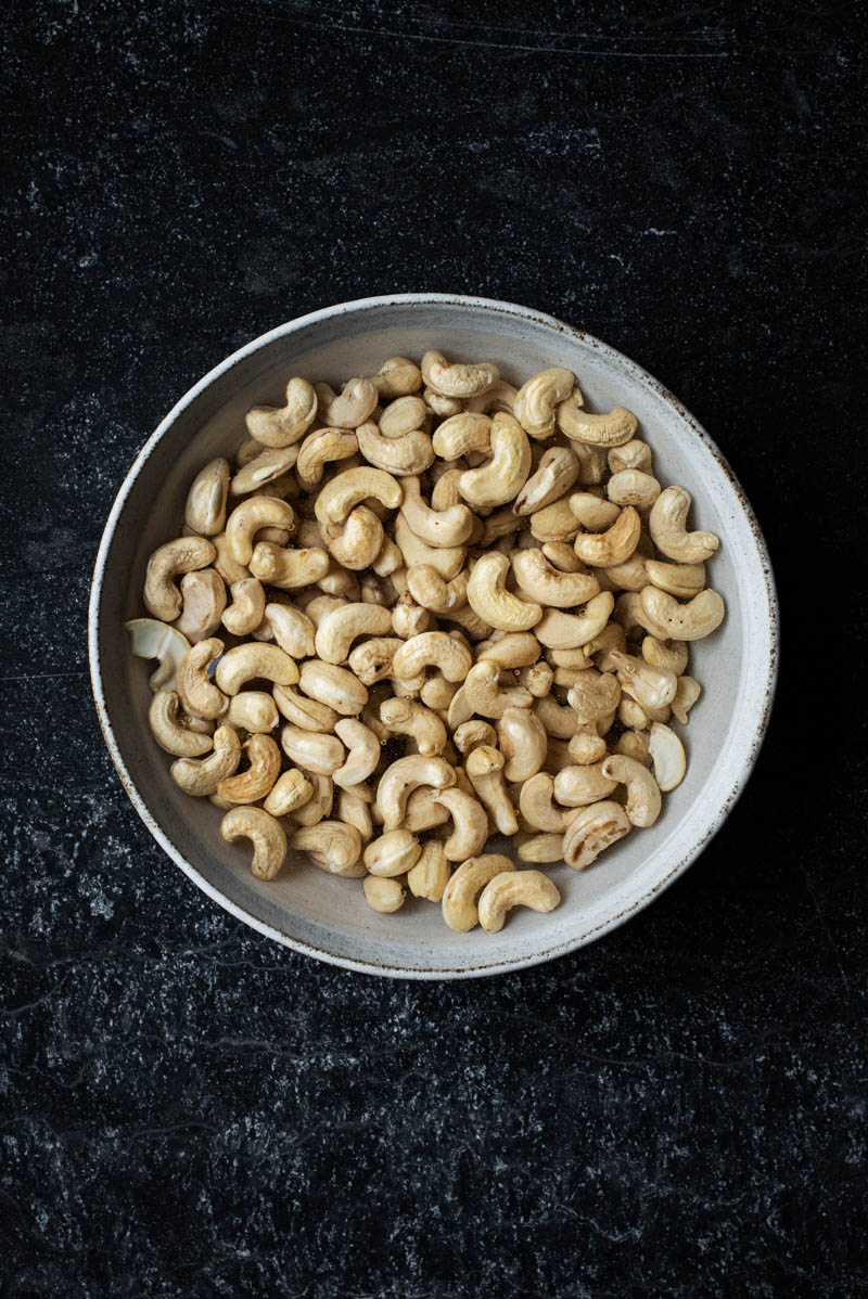 Soaking raw cashews in a shallow bowl.