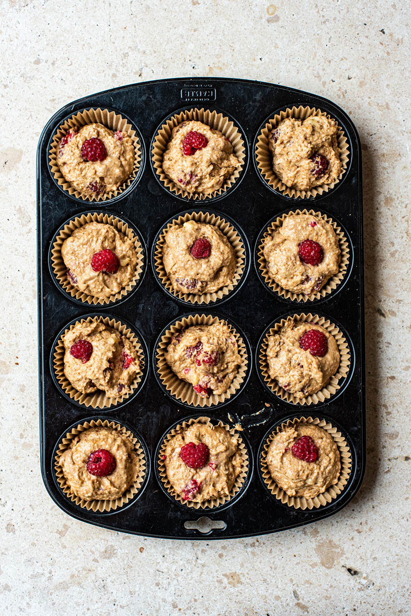 Muffins before baking, topped with extra raspberries.