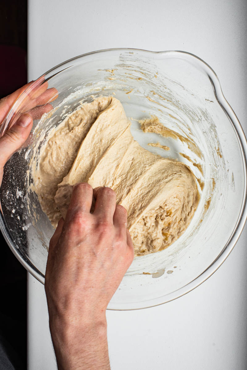 Woman's hands stretching and folding the dough.
