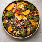 A broccoli and sweet potato lentil bowl with pomegranate seeds.