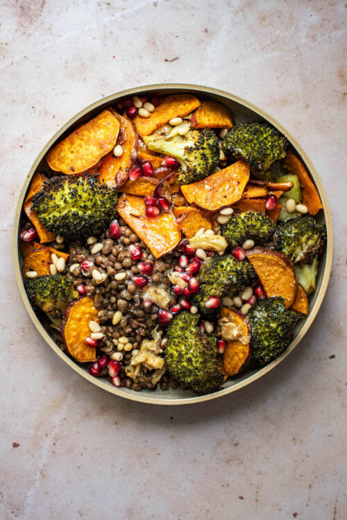 A broccoli and sweet potato lentil bowl with pomegranate seeds.