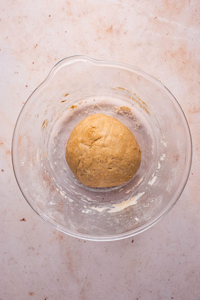 Kneaded dough in a large glass bowl before proving.