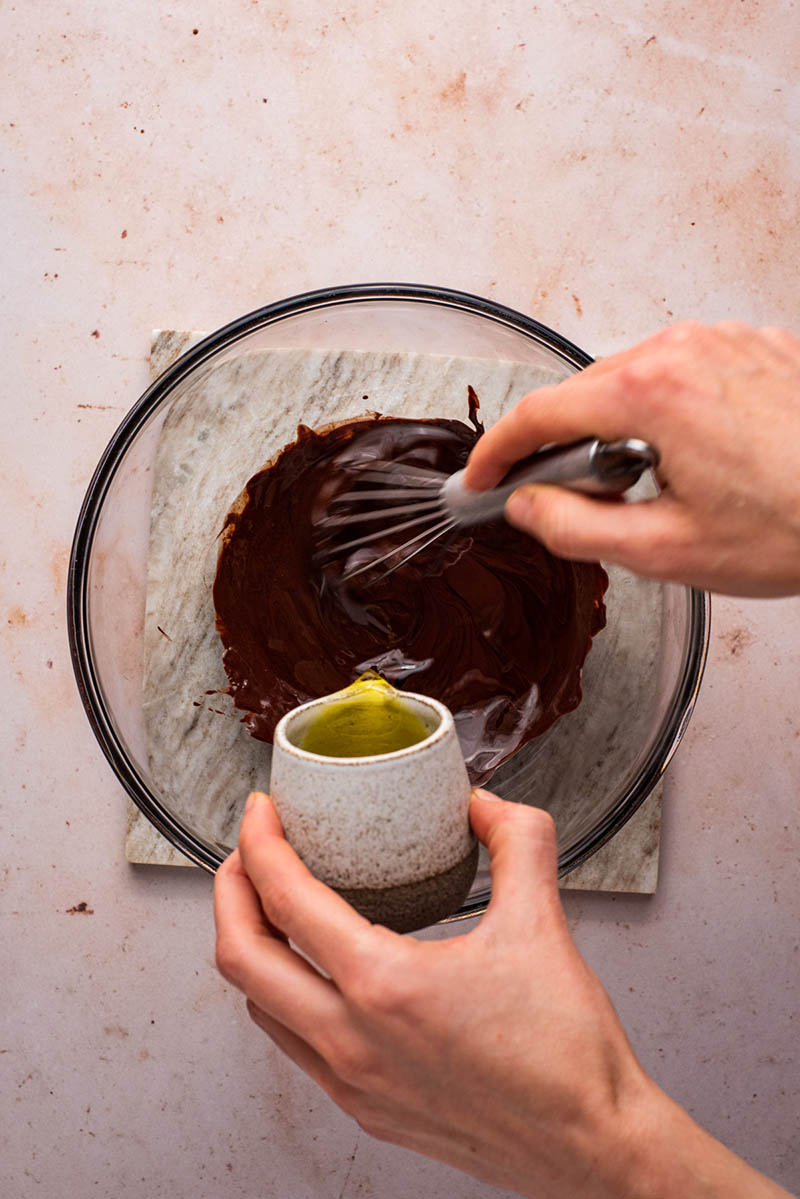 Olive oil being whisked into the melted chocolate.